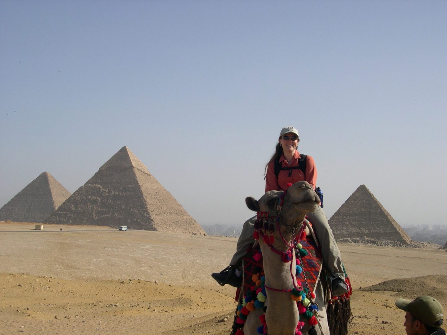 Woman riding a camel in front of Pyramids