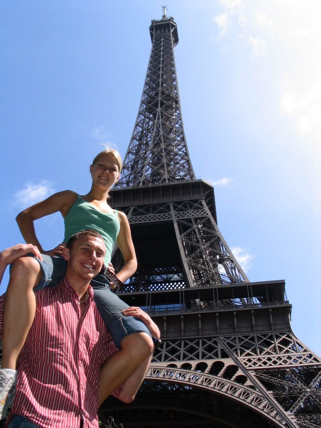 Girl on shoulders of boy in front of Eiffel tower