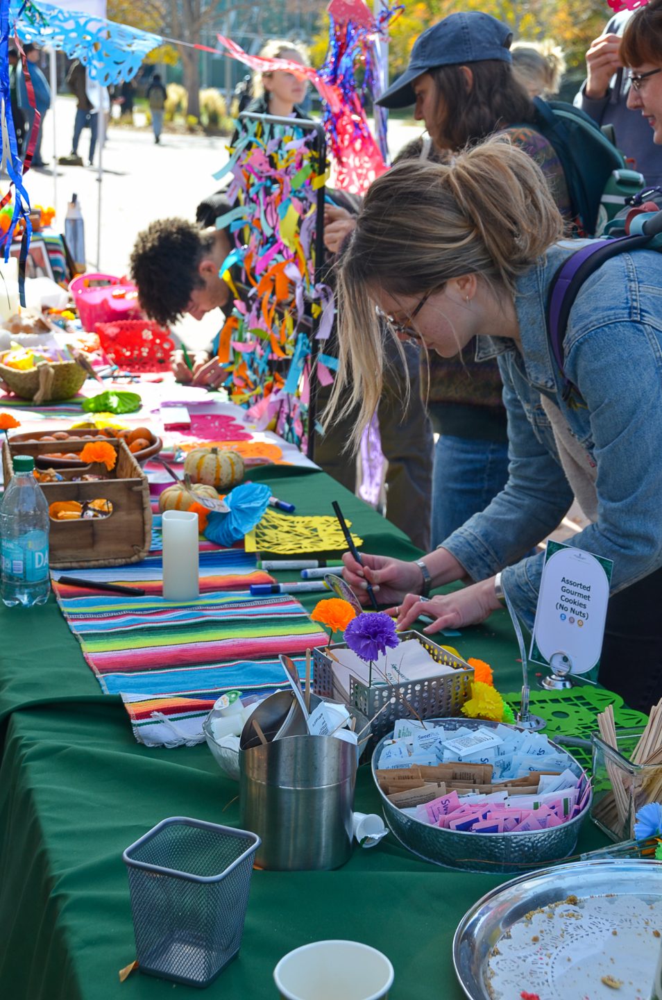 Students and staff write on ribbons to celebrate deceased loved ones during Day of the Dead on the LSC Plaza